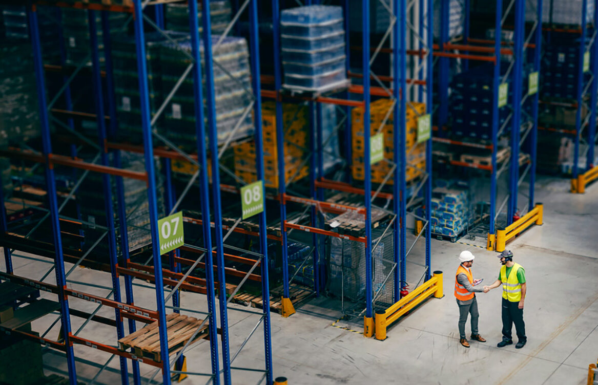 Aerial wide view of two men shaking hands in a warehouse
