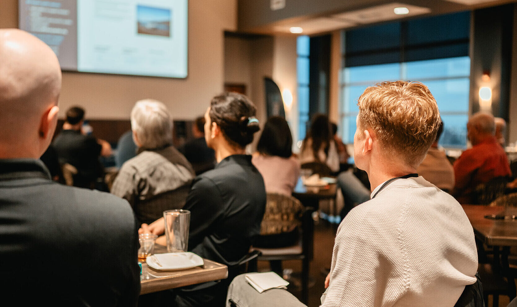 Back photo of people at an event looking at a presentation.
