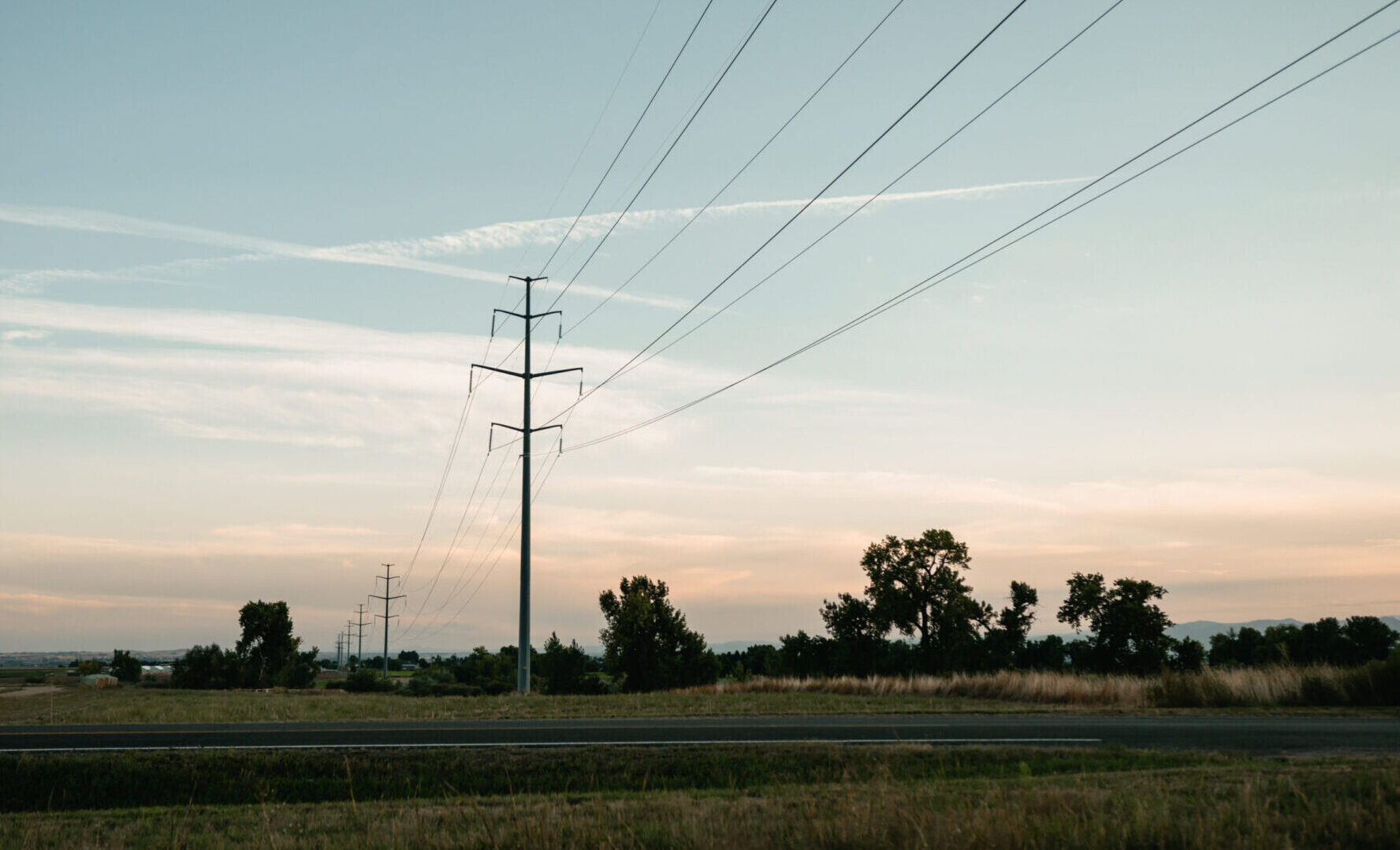 Transmission line on a field with sun setting in the background