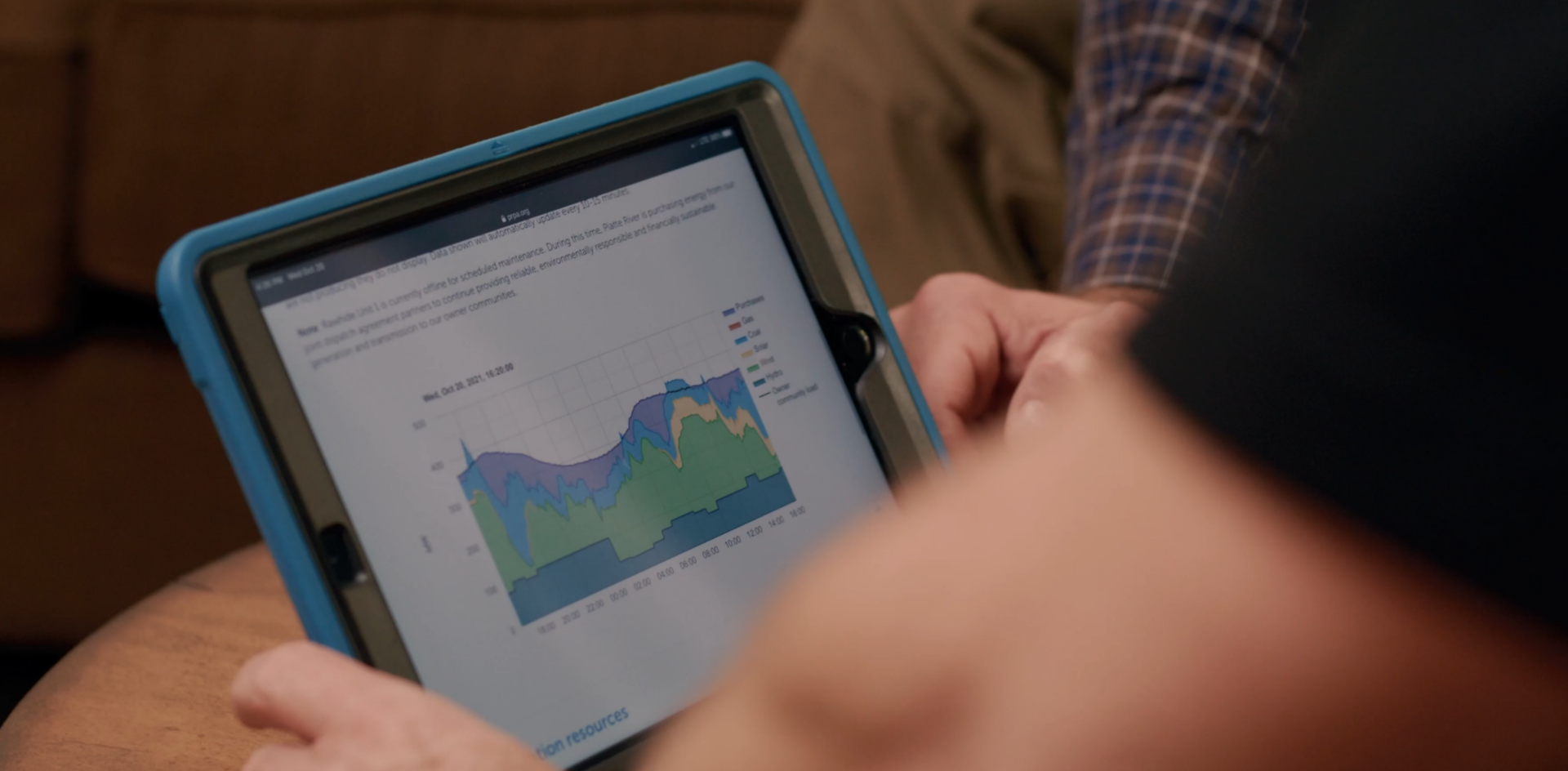 Close up of a man's hands holding an iPad showing Platte River's energy production chart