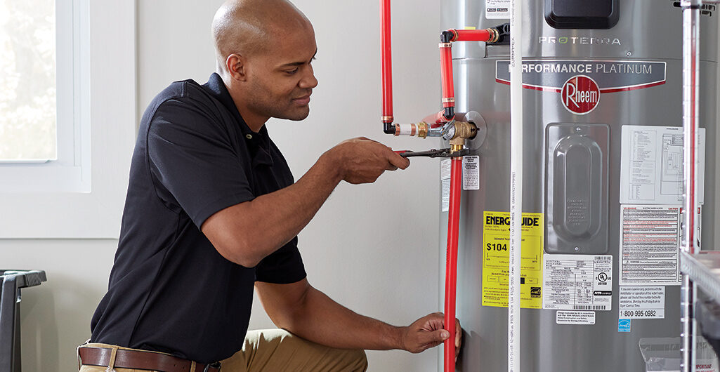 Young African American technician tightening a pipe into a heat pump water heater