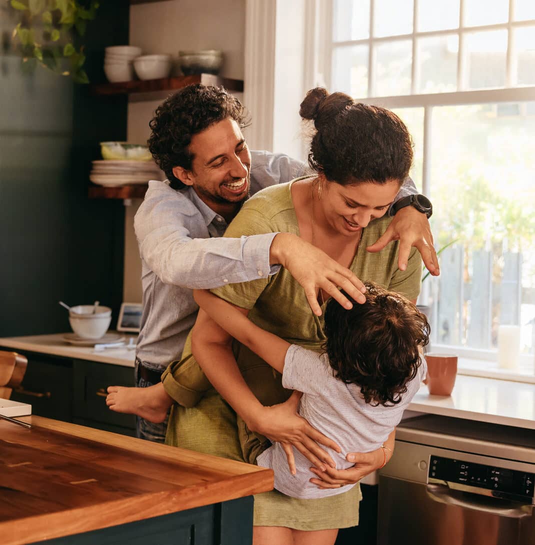 Parents playing with their son in the kitchen. Two happy parents laughing and having fun with their young son at home. Family of three spending some quality time together.