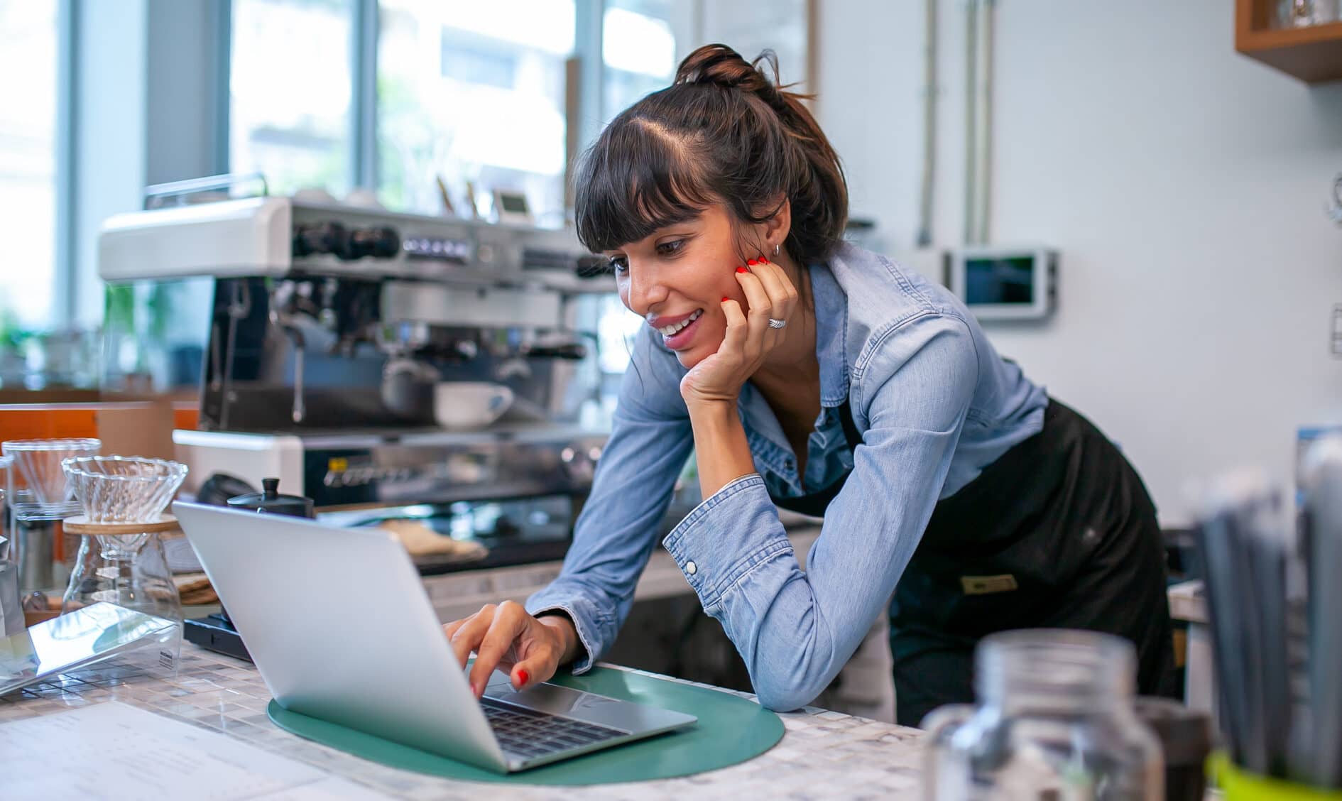 Happy woman barista using laptop for take order from customer in coffee shop.
