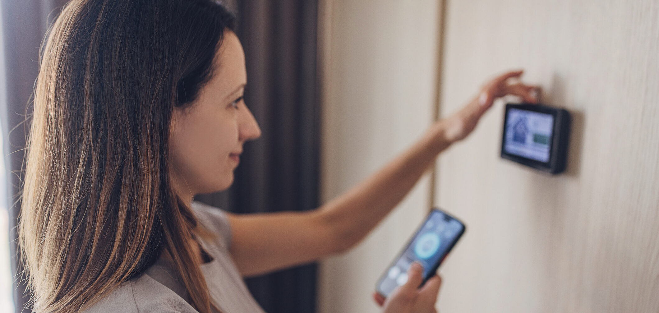 Woman using smart phone to control the smart home device on the wall