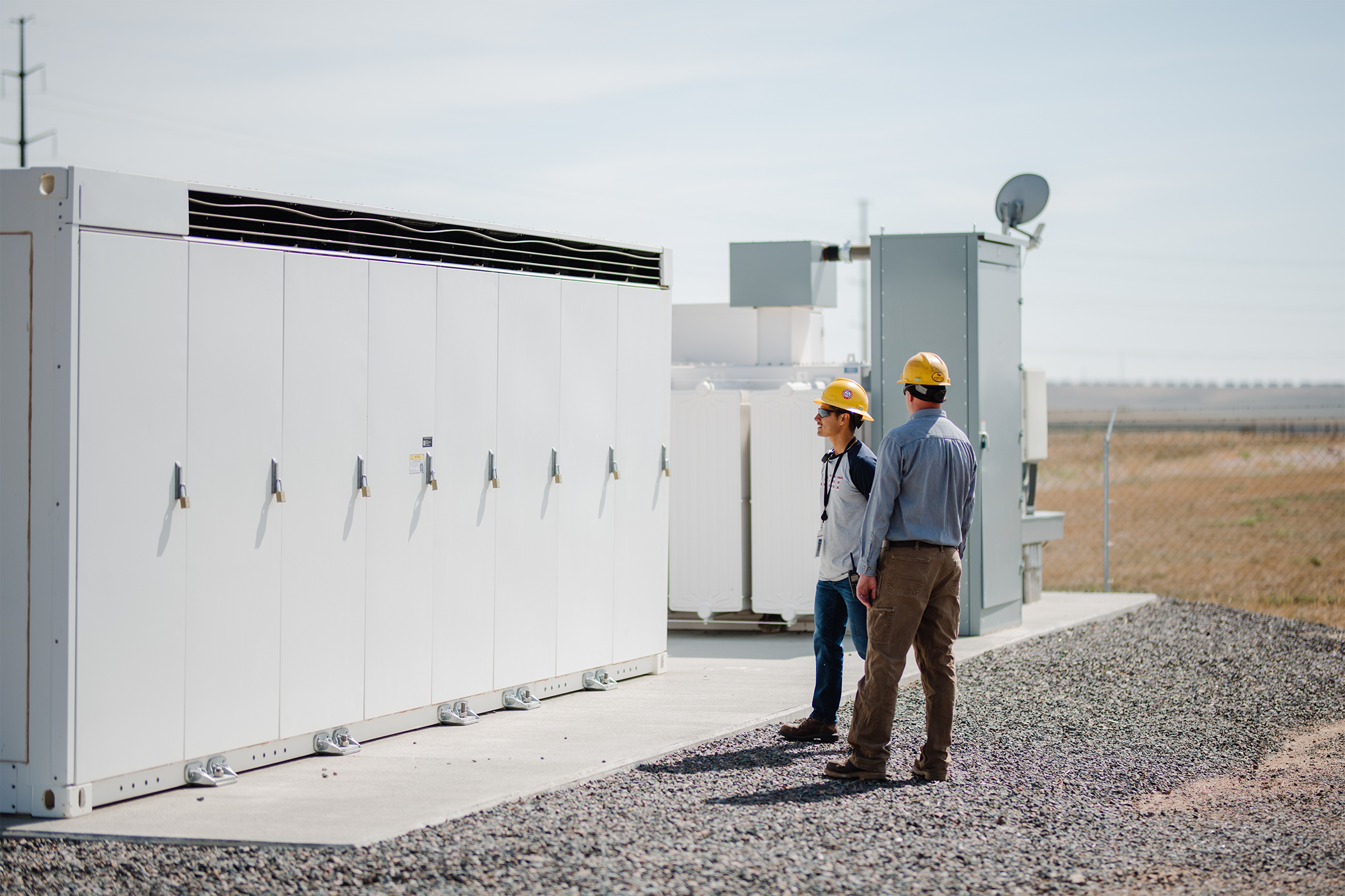 Two men looking at a battery storage unit in a field