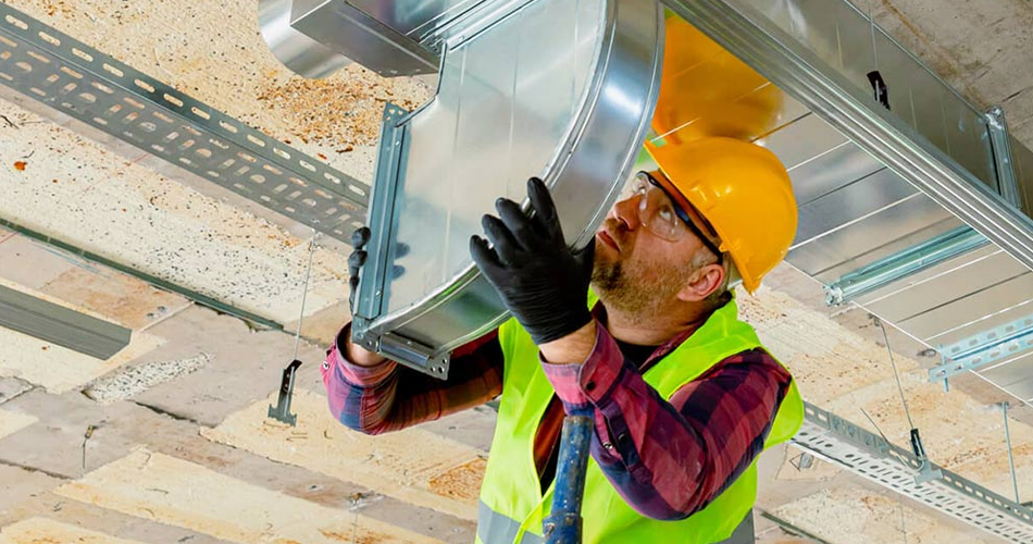 Older man installing AC ducts on a ceiling.