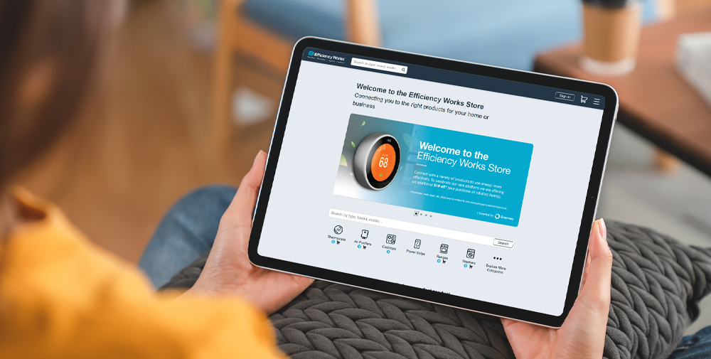 Woman sitting on a couch in her living room browsing the Efficiency Works Store website in her iPad