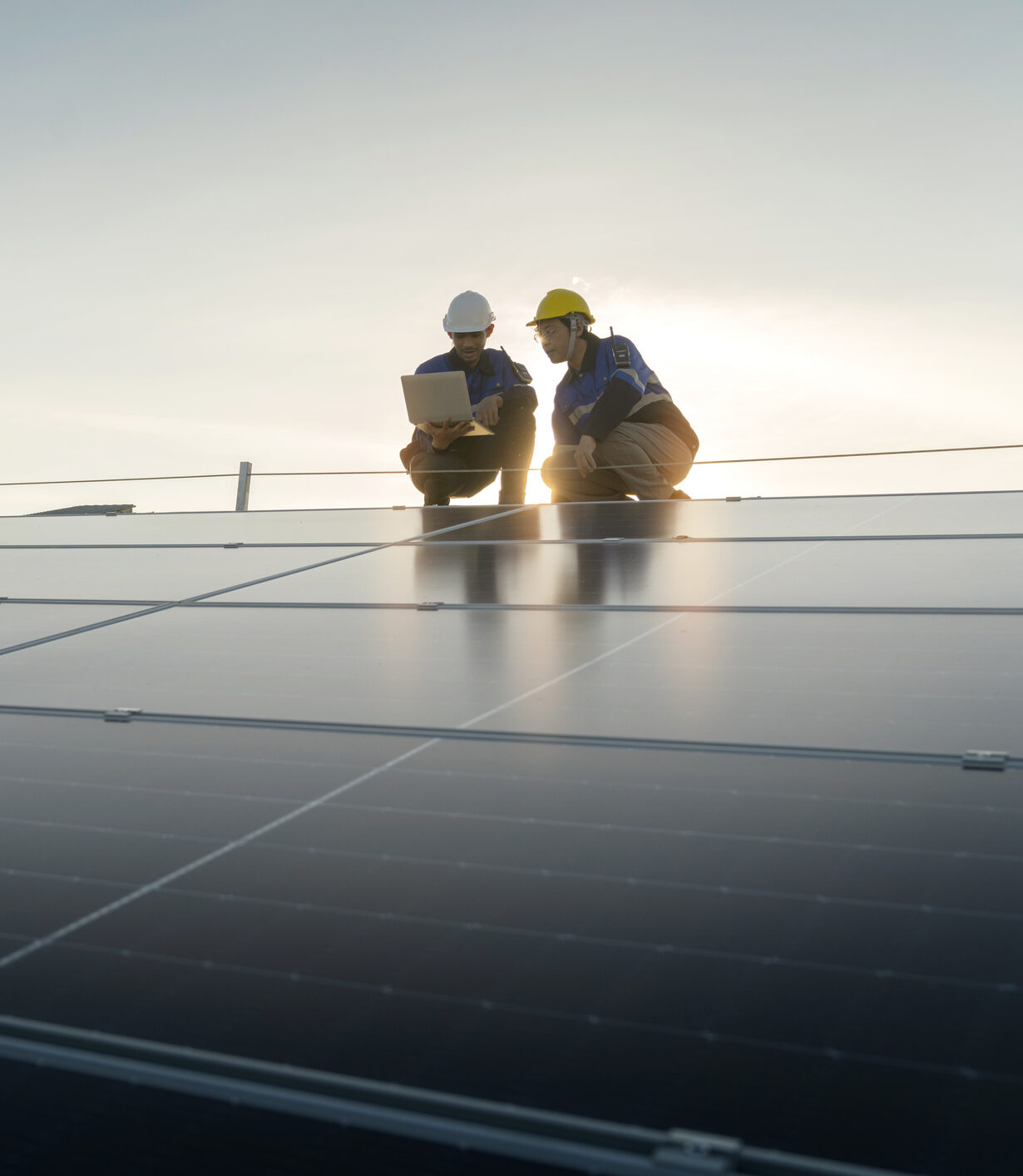 Specialist technician professional engineer with laptop and tablet maintenance checking installing solar roof panel on the factory rooftop under sunlight. Engineers team survey check solar panel roof.