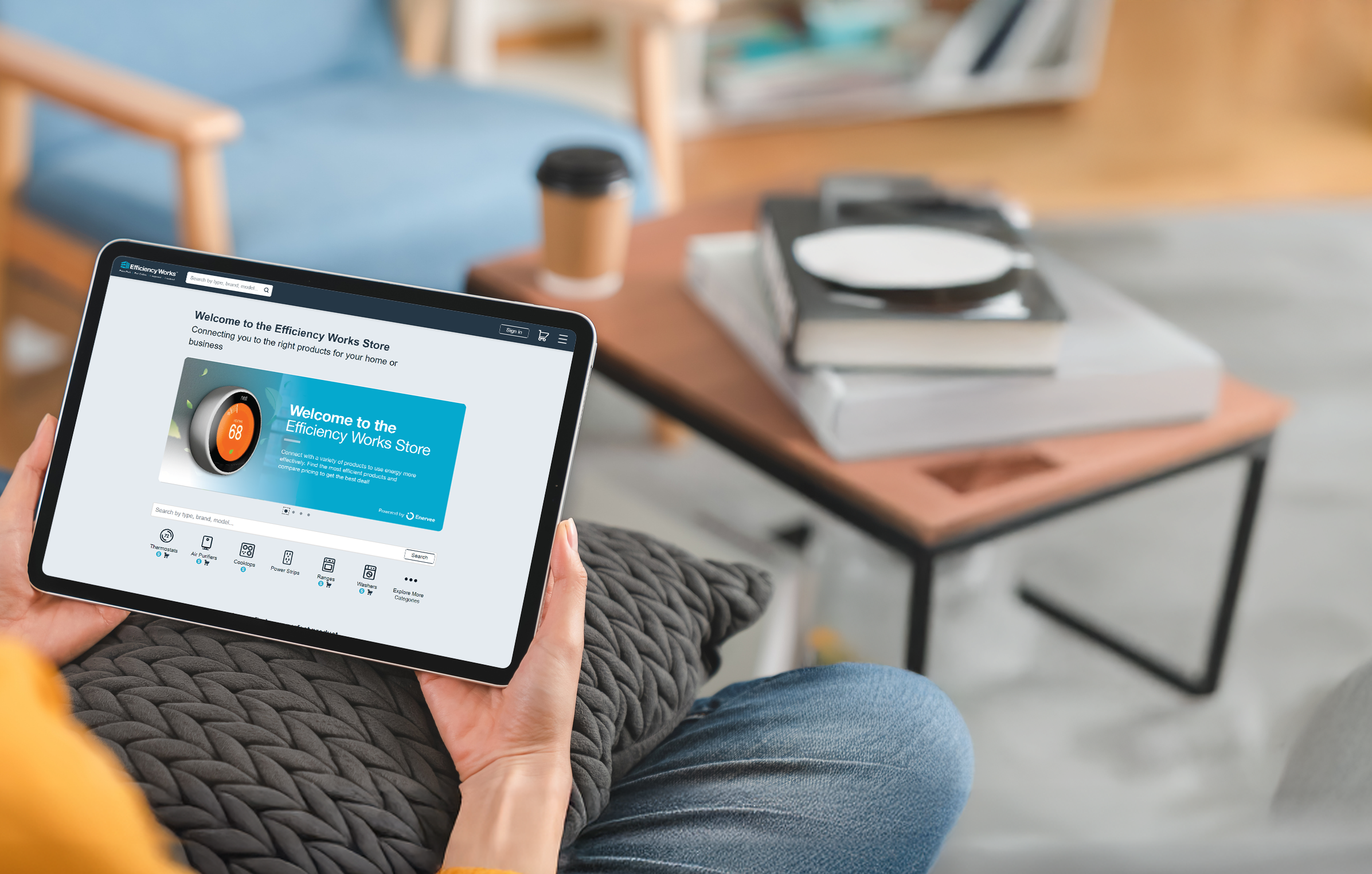 Woman sitting on a couch in her living room browsing the Efficiency Works Store website in her iPad