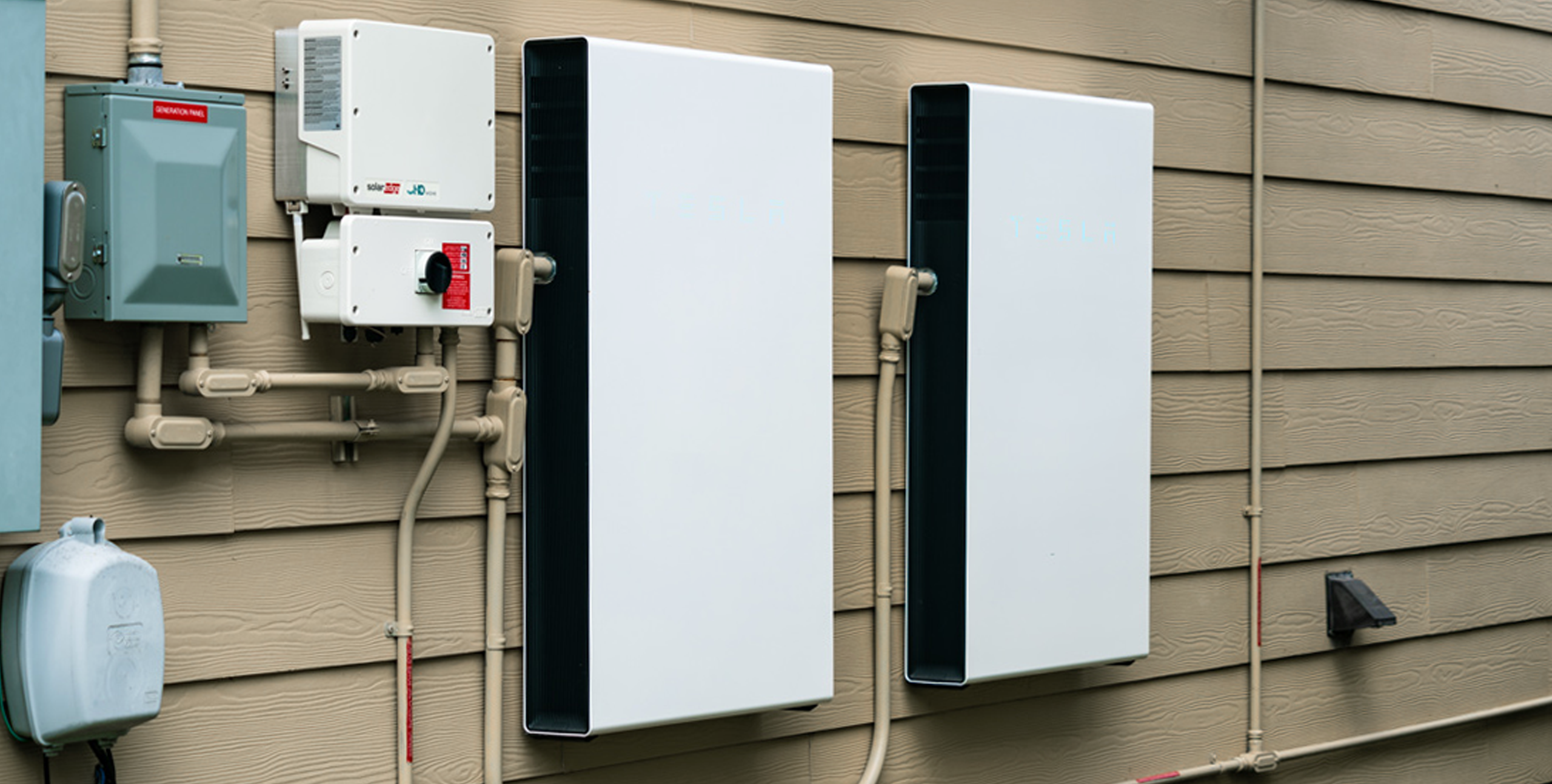 Two battery storage units mounted on the side of a home
