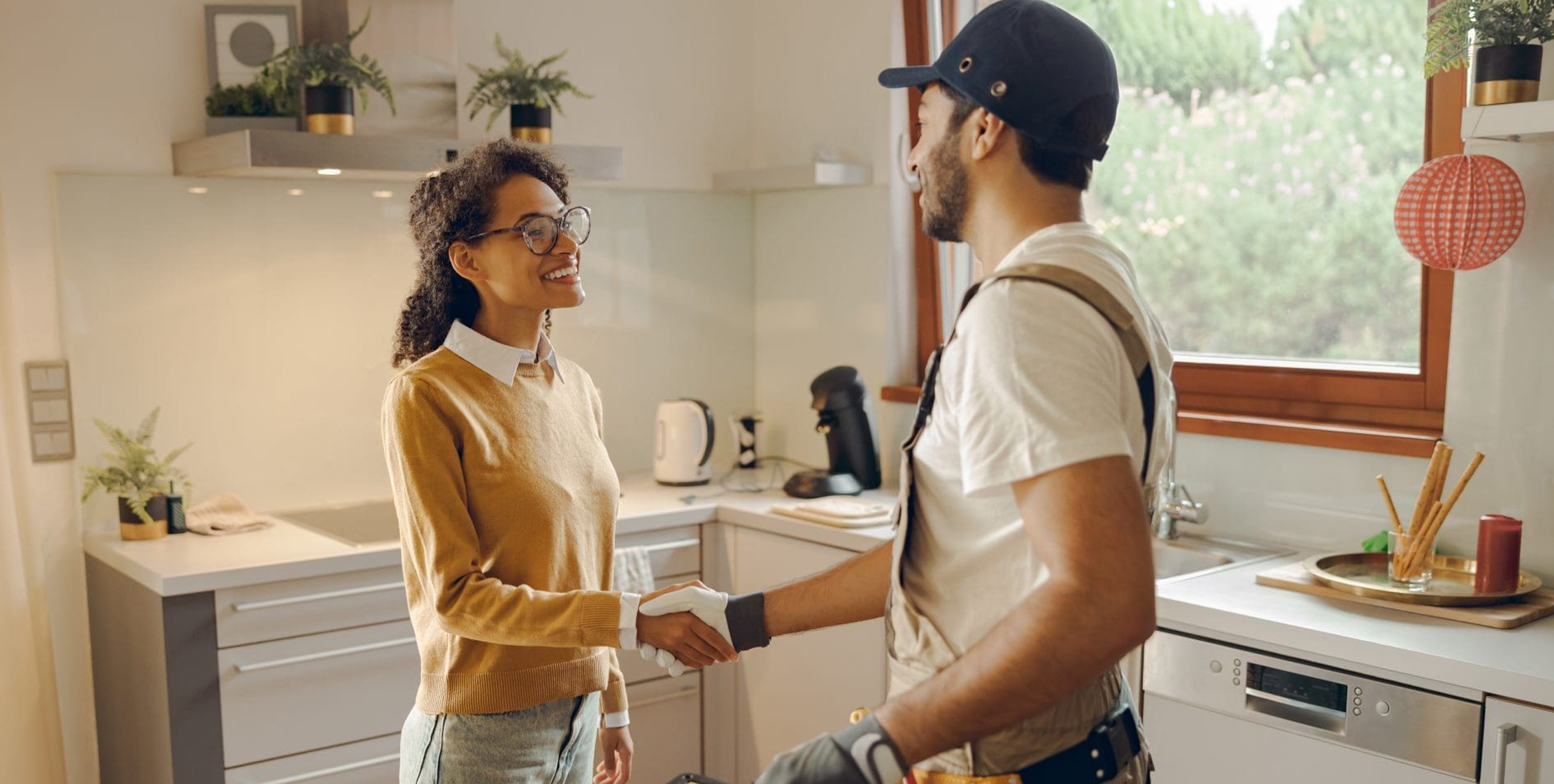 Woman shaking hands with service provider in her kitchen